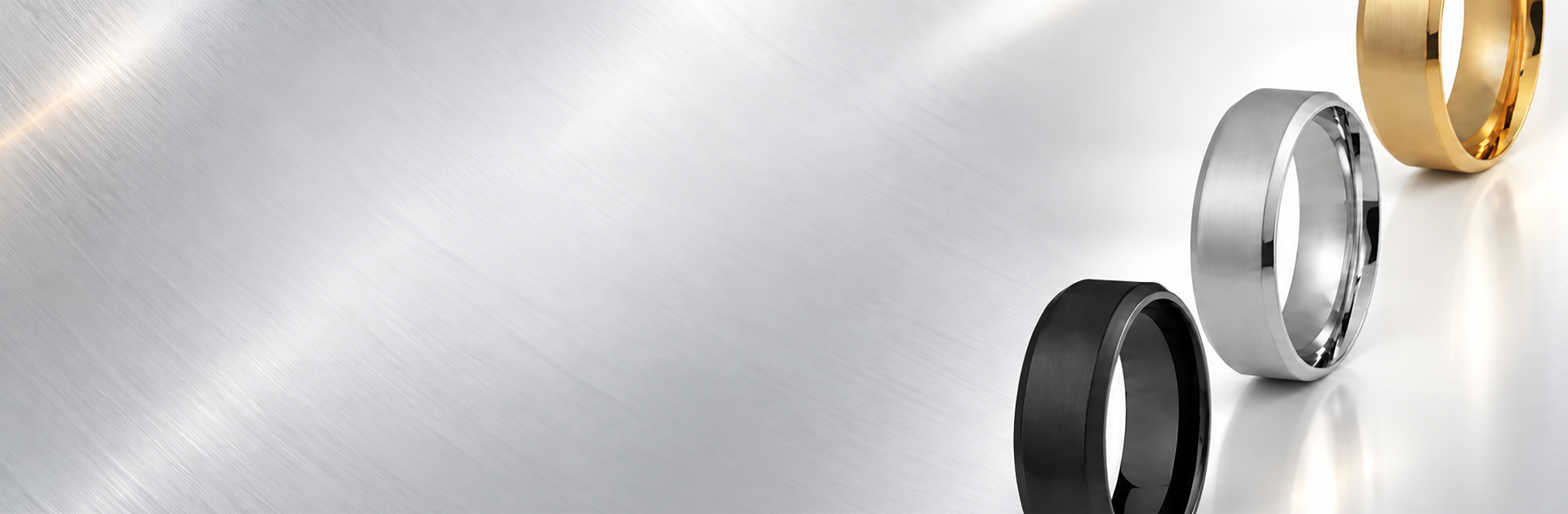 Gold, silver and black rhodium plated rings standing on a brushed metal surface