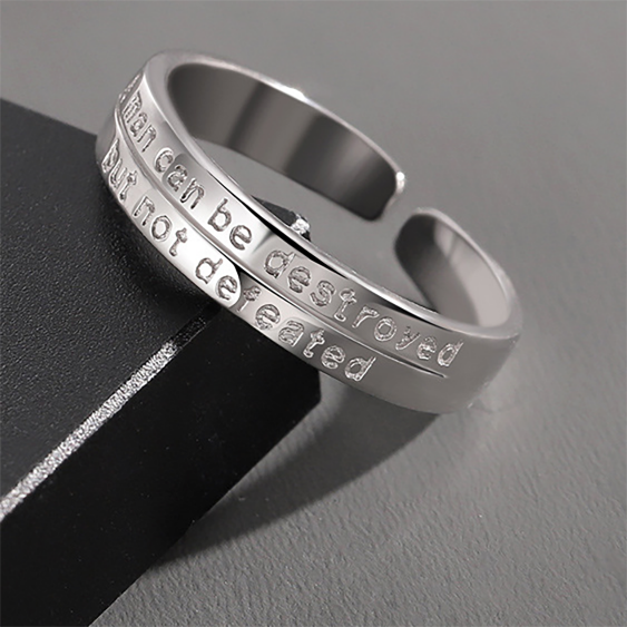 Engraved men's band ring photographed on a dark stone surface