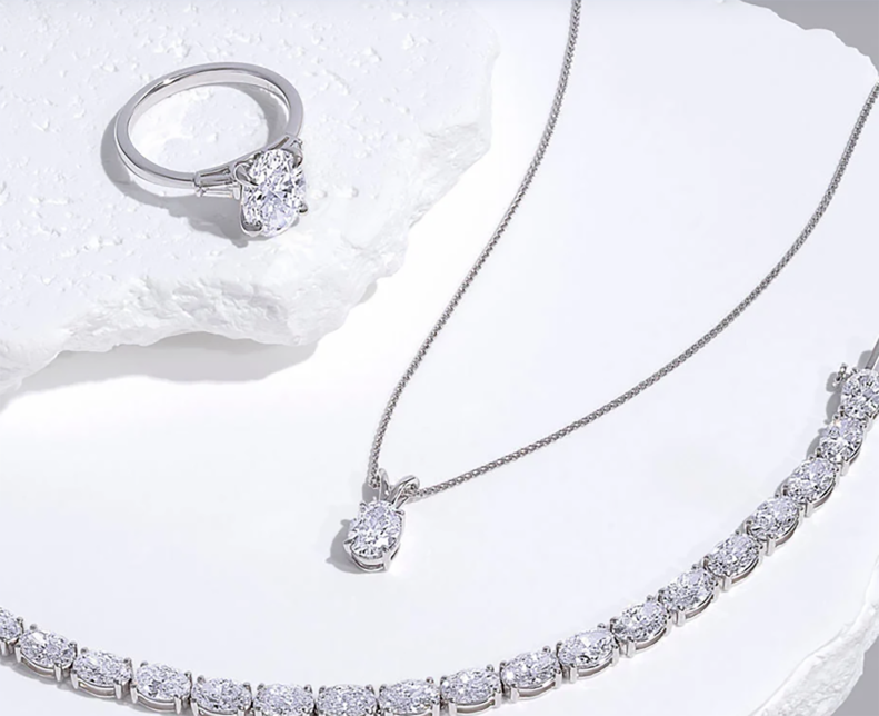 Lab grown diamond ring, pendant necklace and tennis bracelet on white fabric
