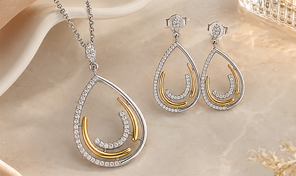 Two tone teardrop pendant and earring set on a soft neutral background