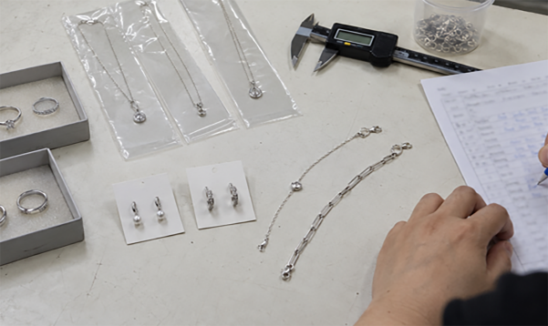 Small batch order laid out for review with trays, chains, calipers and a measurement sheet
