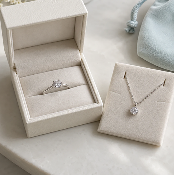 Cream jewelry boxes in paper and fabric finishes reviewed beside a pouch on a workbench