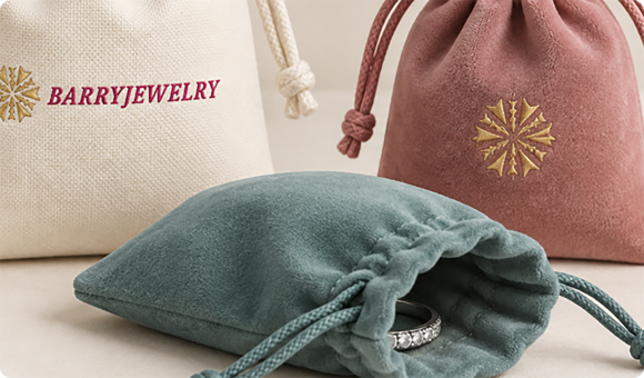 Jewelry pouches in cream, pink and teal fabric with embroidered logo details