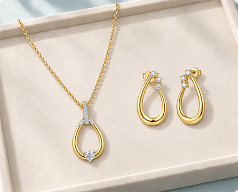 Coordinated gold necklace and drop earrings with matching stone details in a display tray