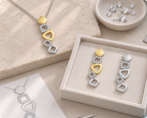 Design sketch of a stone-set pendant next to a tray of finished gold pieces and loose stones