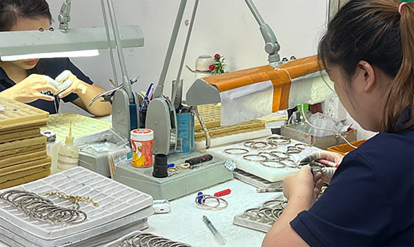 Two inspectors checking finished jewelry at a workbench during final quality control