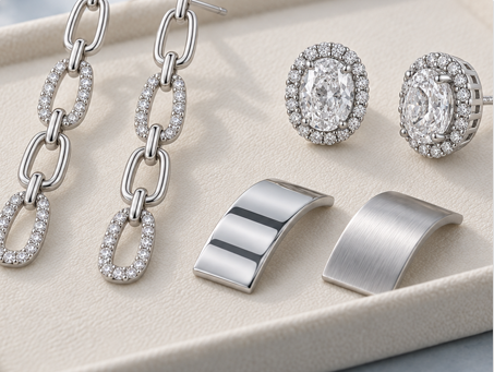 Sterling silver chain links, curved metal plates and pavé halo earrings arranged on a sample tray